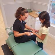 Chiropractor consulting with a young patient beside an adjusting table