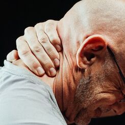 Person holding the back of their neck in pain